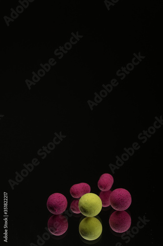 bright green, red boilies, fishing baits for carp isolated on dark background. photo