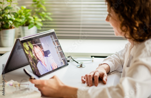 telemedicine concept elderly woman using laptop and taking her blood pressure photo