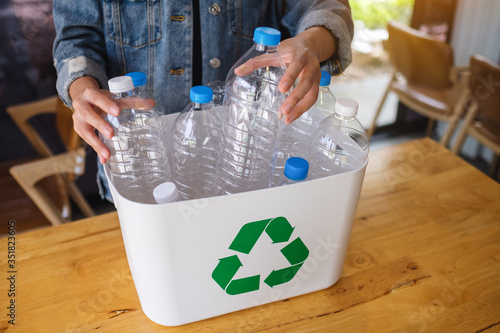 A woman collecting and separating recyclable garbage plastic bottles into a trash bin at home