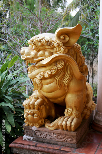 Golden lion with a ball under its paw at the entrance to a Buddhist temple, Phu Quoc