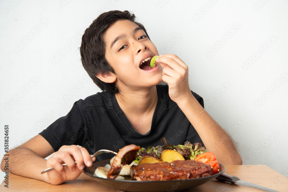 Little boy eating rib pork grill with happy face Little boy eating rib pork grill with happy face