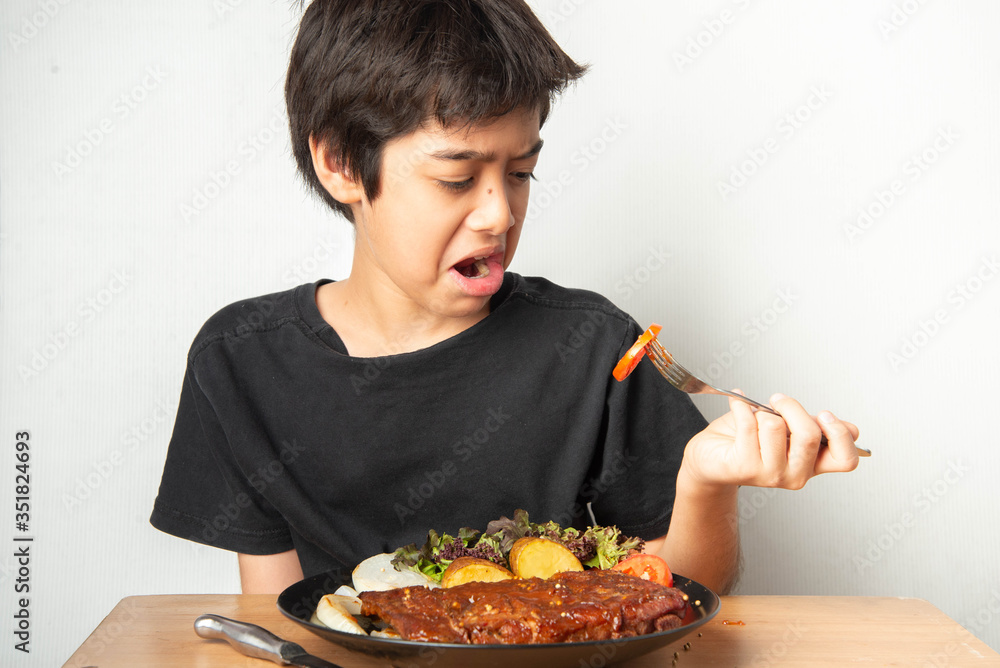 Little boy teenager eating tomato with salad for his meal Little boy teenager eating tomato with salad for his meal