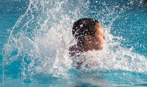 A boy swims in the pool with spray