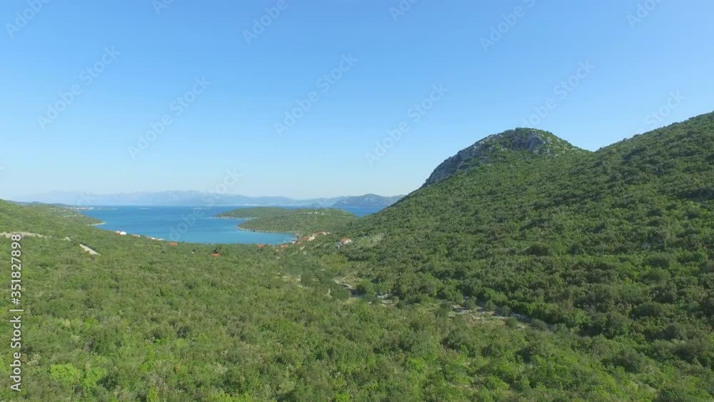 Aerial shot of beautiful green landscape against blue sky, drone is flying upwards - Ston, Croatia Aerial shot of beautiful green landscape against blue sky, drone is flying upwards - Ston, Croatia