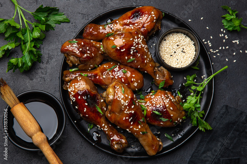Bild auf Leinwand spicy teriyaki chicken legs on black plate
