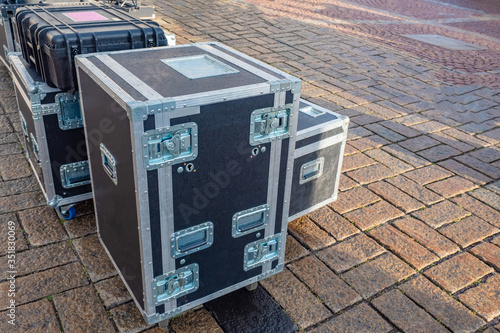 Boxes with reinforced corners, handles and wheels on the city sidewalk. Containers for concert equipment on the background of paving stones. Preparing for a street concert. Suitcases for props.