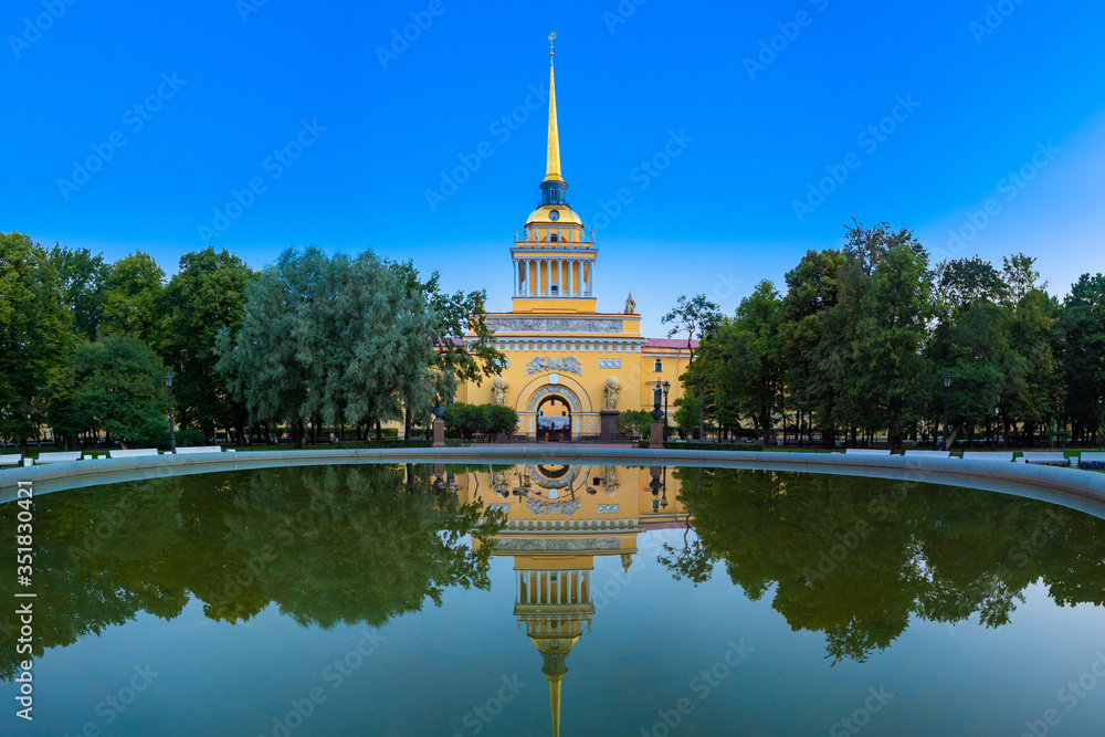 Fototapeta premium Saint Petersburg. Russia. The Admiralty building is reflected in the water. Admiralty on the background of water in the fountain. A Golden spire with a ship against the blue sky. Summer in Petersburg.