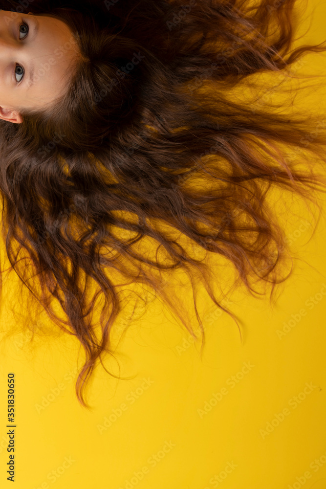 The girl lies on a yellow background with her hair. The girl lies on a yellow background with her hair.