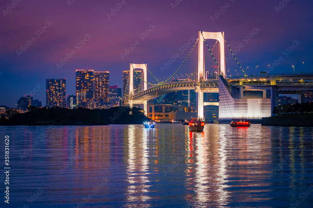 Japan. Boating on Tokyo Bay at sunset. Rainbow bridge on the background of the evening city. White suspension bridge in Japan. Attraction In Tokyo. The Island Of Odaiba.