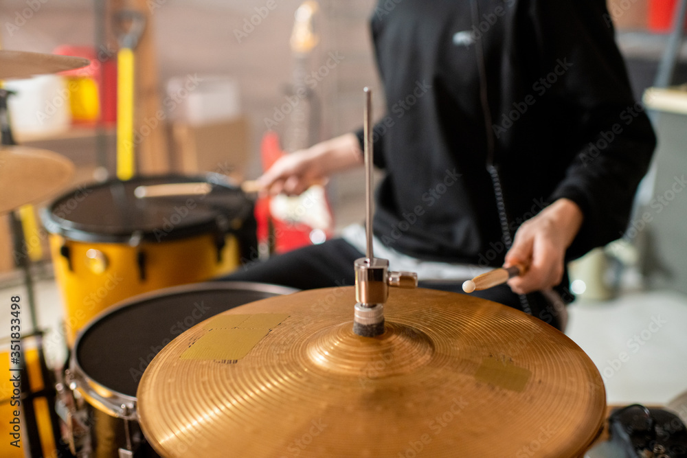 Obraz premium Hand of young musician in black hoodie holding drumstick over cymbals
