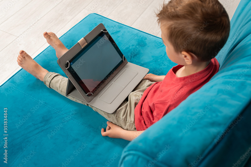 Fototapeta premium Preschooler watches tablet at home. Leisure at home