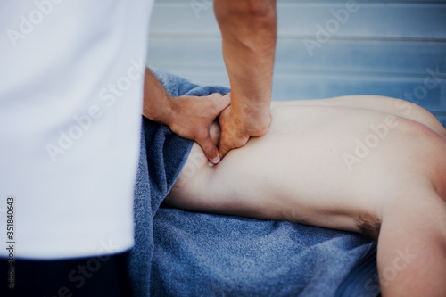 Sport therapist giving lower back massage to injured athlete