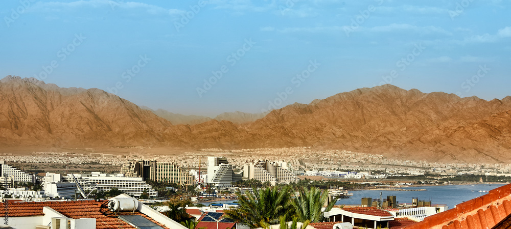 Panoramic view on beach of the Red Sea in Eilat famous resort and recreation town in Israel and Aqaba cities - Jordan