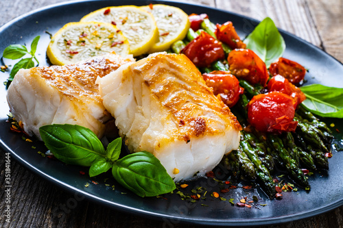 Canvas Print Fish dish - fried cod fillet with asparagus on wooden table