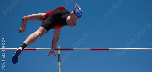 Competition pole vault jumper male on blue sky background