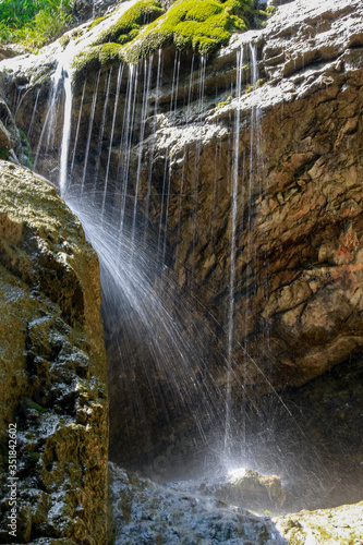 Wasserfäden laufen von Felsen und glitzern im Sonnenlicht