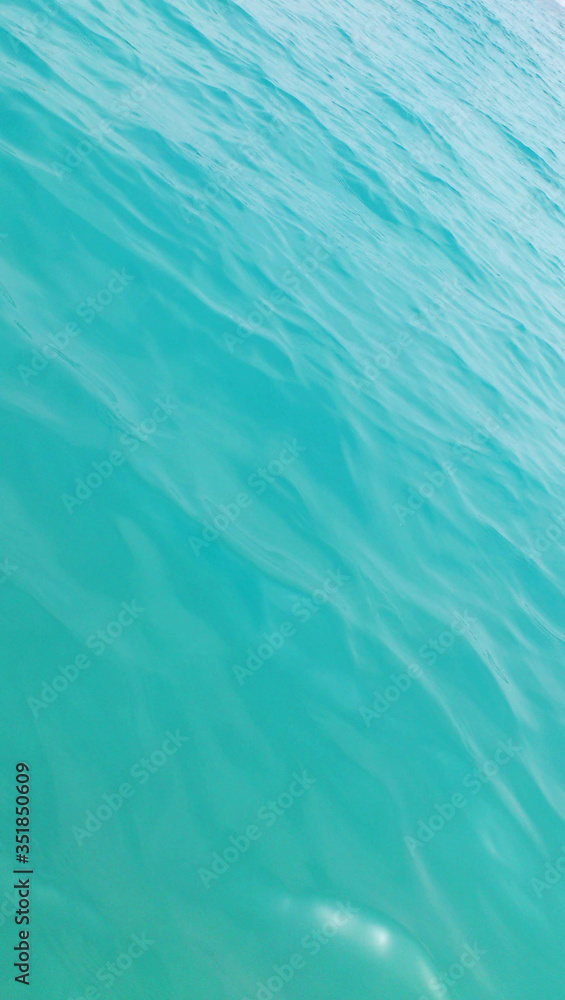 Turquoise background. The surface of the sea water. Vertical format.