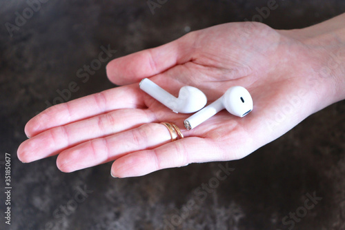 White wireless headphones in a hand. Headphones in a female hand.