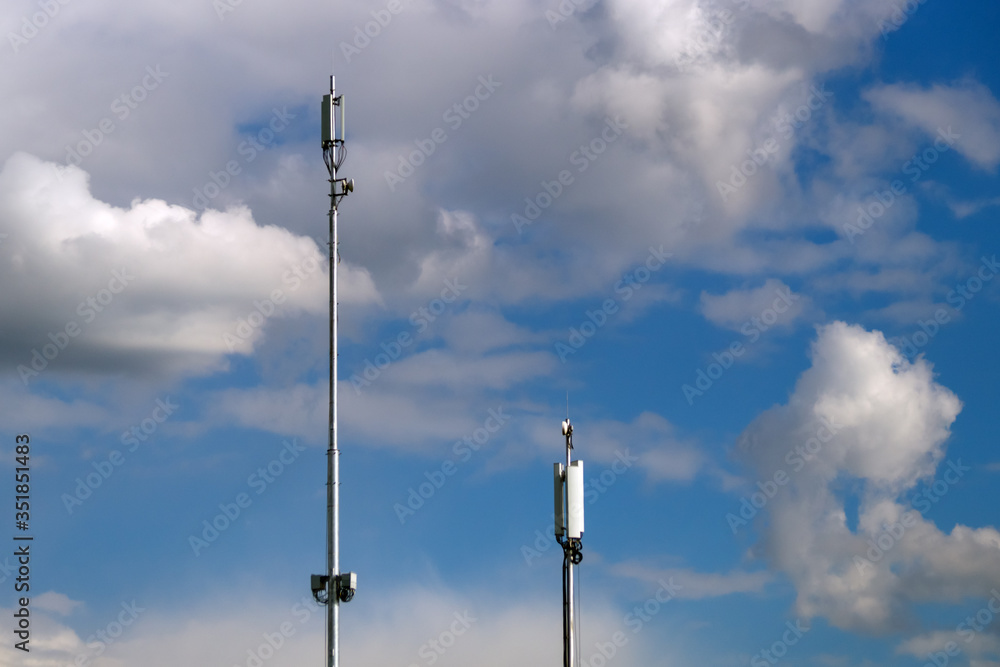 two cellular antennas against a cloudy sky