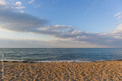 Smooth lines of sand, sea and sky with clouds on background. 