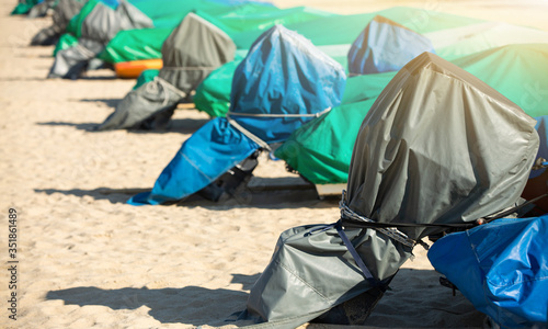 Motor boats under the covers on a beach near the sea during coronavirus lockdown