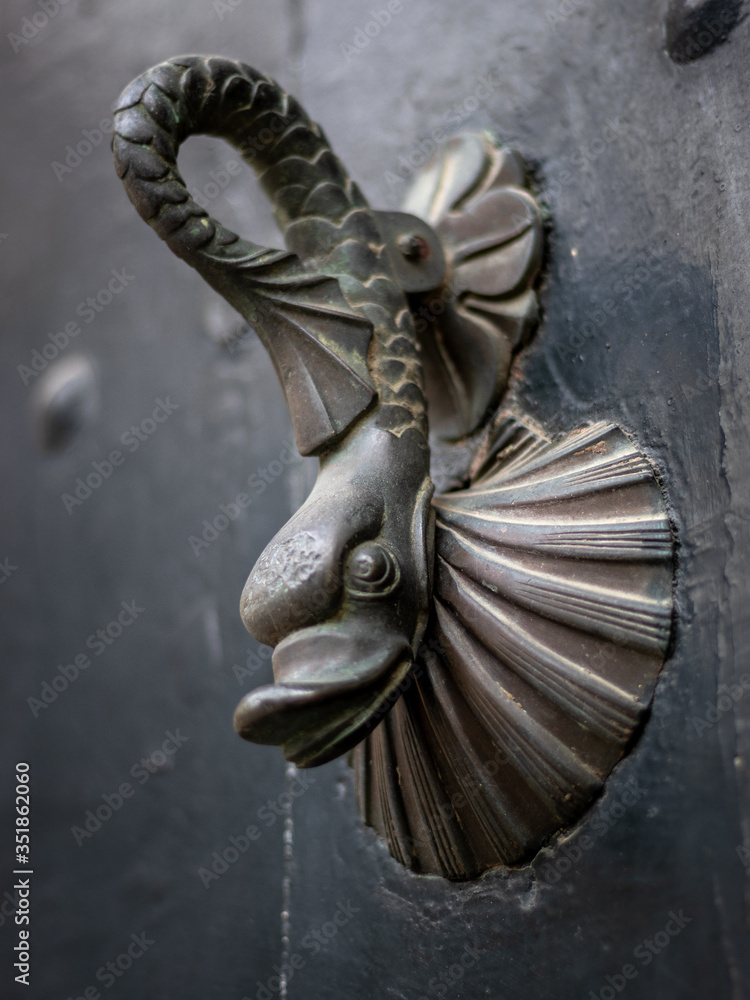 Obraz premium Street photography of an old doorhandle with a beautiful grey fish shape on top of a conch shell