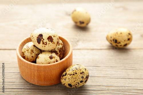 Fresh quail eggs in bowl on grey wooden background