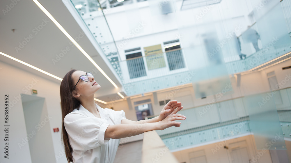 Portrait of a young positive business woman. A girl in glasses and a white shirt, the interior of a business center, Portrait of a young positive business woman. A girl in glasses and a white shirt, the interior of a business center,