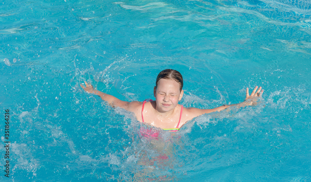 the girl is learning to swim and may drown, floundering with her hands in the water. Child having fun in swimming pool.