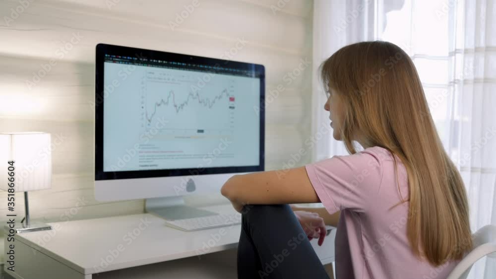 Girl works at the computer in a homely atmosphere and watches graphics. Stocks increase and decrease. Girl works at the computer in a homely atmosphere and watches graphics. Stocks increase and decrease.