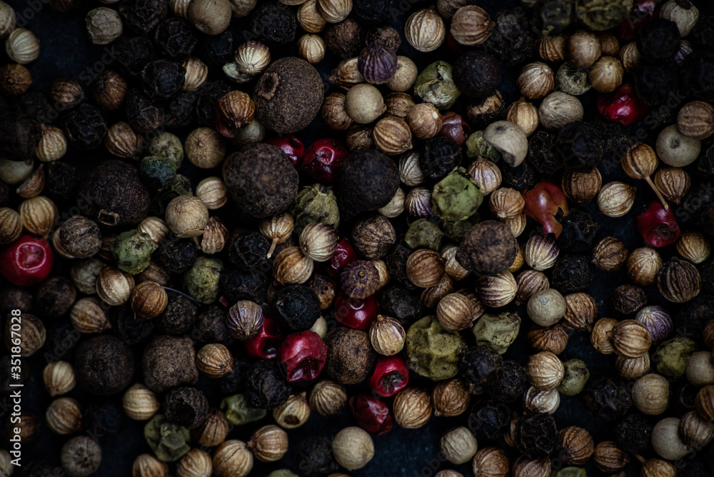 Obraz premium Colourful rainbow peppercorns on a black dark slate background.