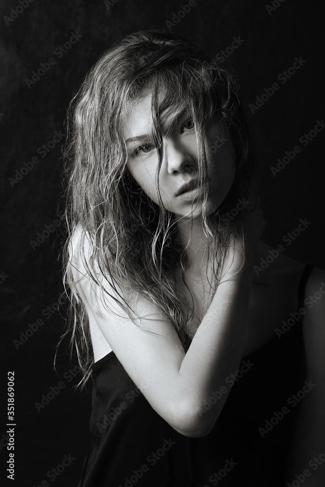wet curly hair covers the face of a young girl, smooth skin, attractive girl.seductive look, black and white photo, deep shadows, black little dress,