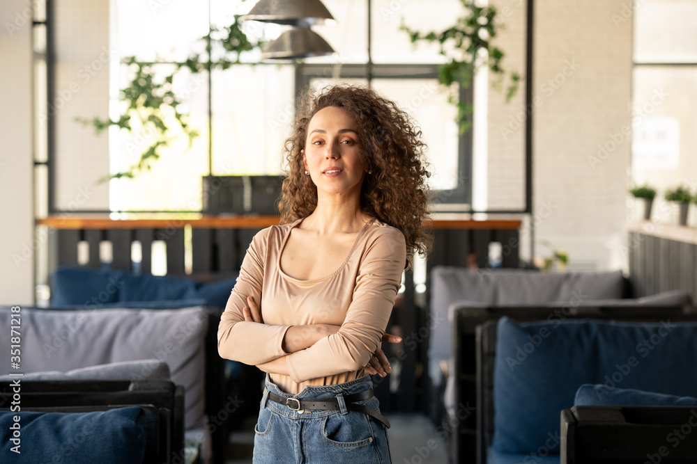 Young successful businesswoman standing inside luxurious cafe or restaurant