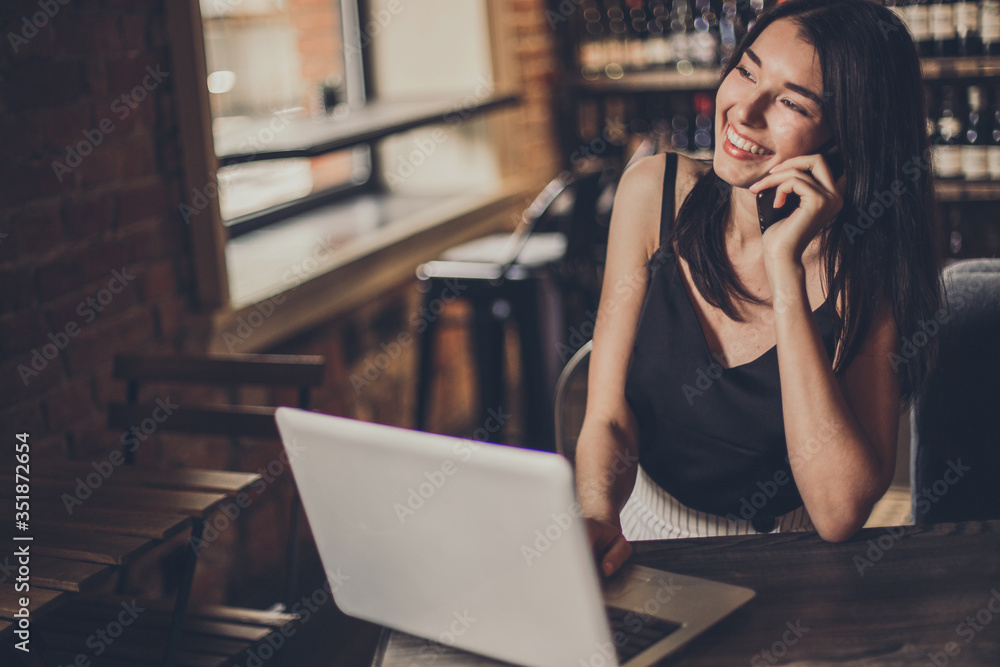 Business woman working on a laptop and using phone in a cafe. Business woman working on a laptop and using phone in a cafe.