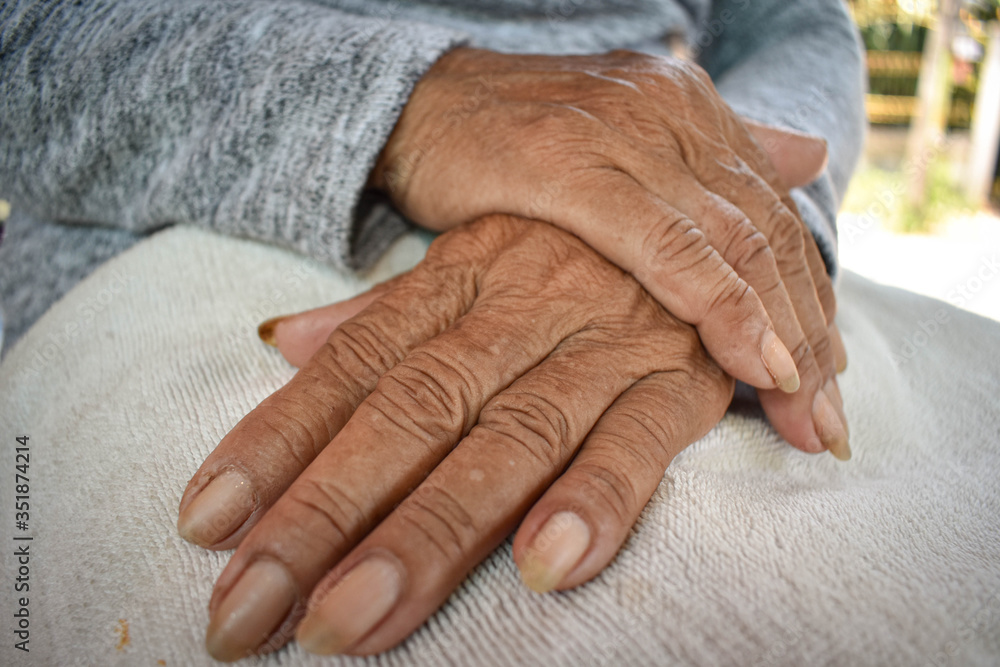 Fototapeta premium The hand of the sick old woman rests on the lap. Mental health care at home.