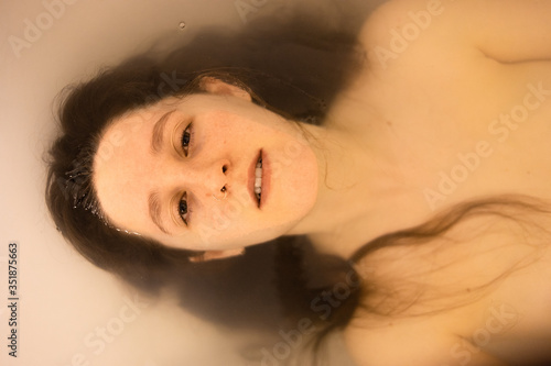 portrait of girl in the bathtub, serious, lonely, half submerged
