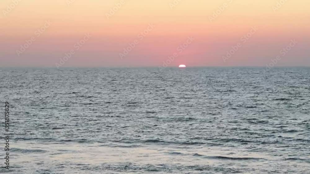 Cloudless horizon & Pink purple blue sunset sky with bright yellow red twilight over calm ocean waves & sea water surface at beautiful golden evening in tropical summer or spring sunlight & sun rays Cloudless horizon & Pink purple blue sunset sky with bright yellow red twilight over calm ocean waves & sea water surface at beautiful golden evening in tropical summer or spring sunlight & sun rays