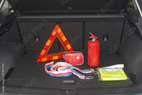 Travel kit in the trunk of a car. Fire extinguisher, tow rope, warning triangle, medical kit, reflective vest.