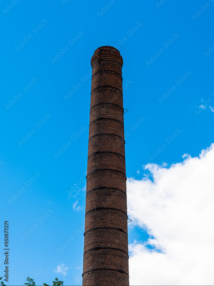 Big old broken brick pipe against the sky and a white cloud