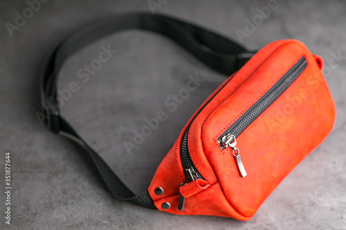 Red waist bag made of leather, banana on a gray background.