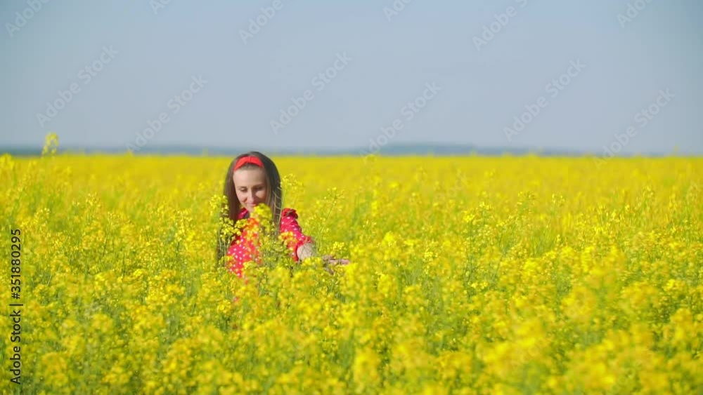 girl walks across the field with canola flowers girl walks across the field with canola flowers
