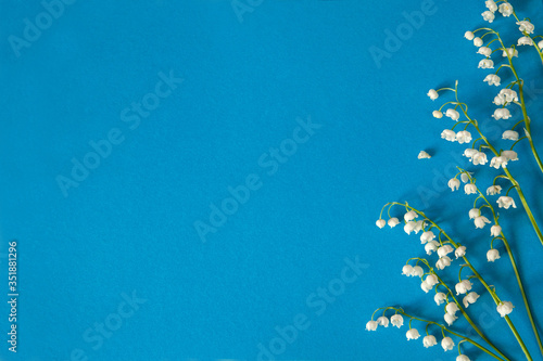 Flower composition. Border of flowers of the may lily of the valley (Convallaria majalis) on a light blue paper background. Free space. 