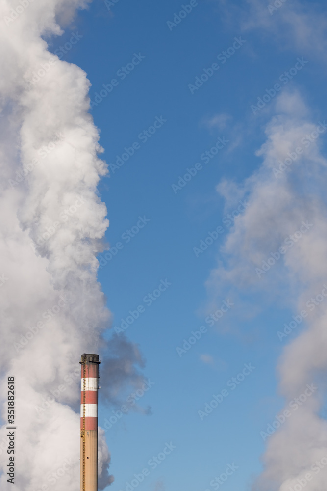 Cooling towers and Chimneys of a coat-fired power plant fuming white smoke with blue sky background.