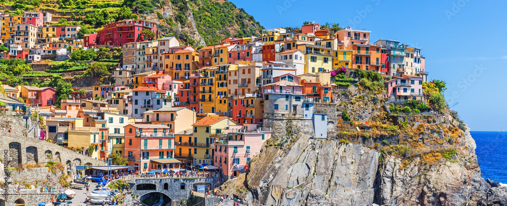 Panoramic view of Manarola village in Cinque Terre famous UNESCO travel destination in Italy. Colorful houses at cliff, ancient European village at Mediterranean sea.