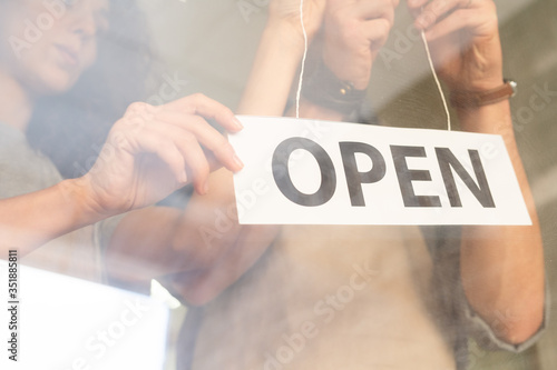 Slika na platnu Hands of young man hanging paper notice announcing open on the door