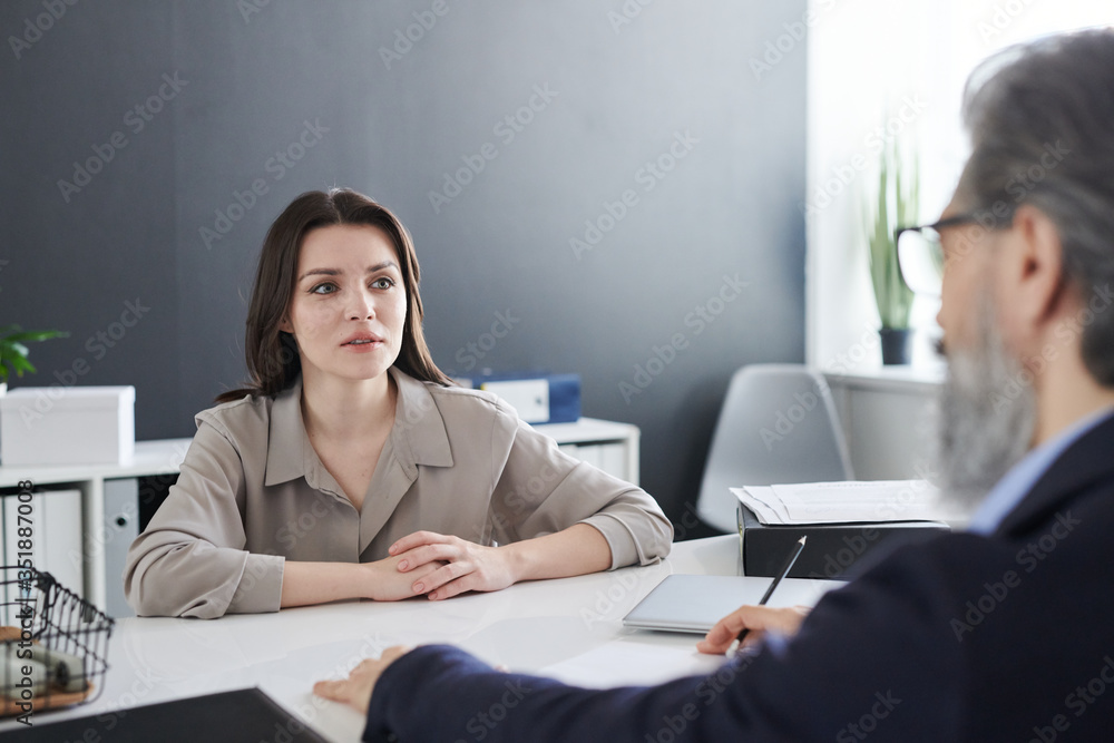 Young elegant brunette female looking at her psychotherapist during talk Young elegant brunette female looking at her psychotherapist during talk