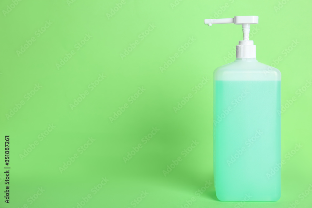 Dispenser bottle with antiseptic gel on green background. Space for text