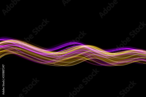 Fototapeta Naklejka Na Ścianę i Meble -  Long exposure photograph of neon pink and gold colour in an abstract swirl, parallel lines pattern against a black background. Light painting photography.