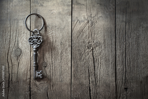 old iron  big retro key hanging on a nail against a rustic wooden wall, concept of secret, inheritance, opportunity