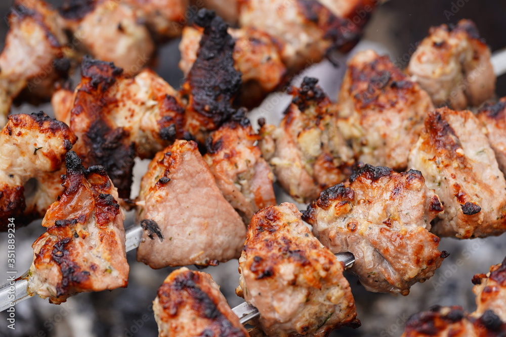 Close up of toasted shashlik on skewers. Succulent barbecue roasting on chargrill. Concept of picnic outdoor.